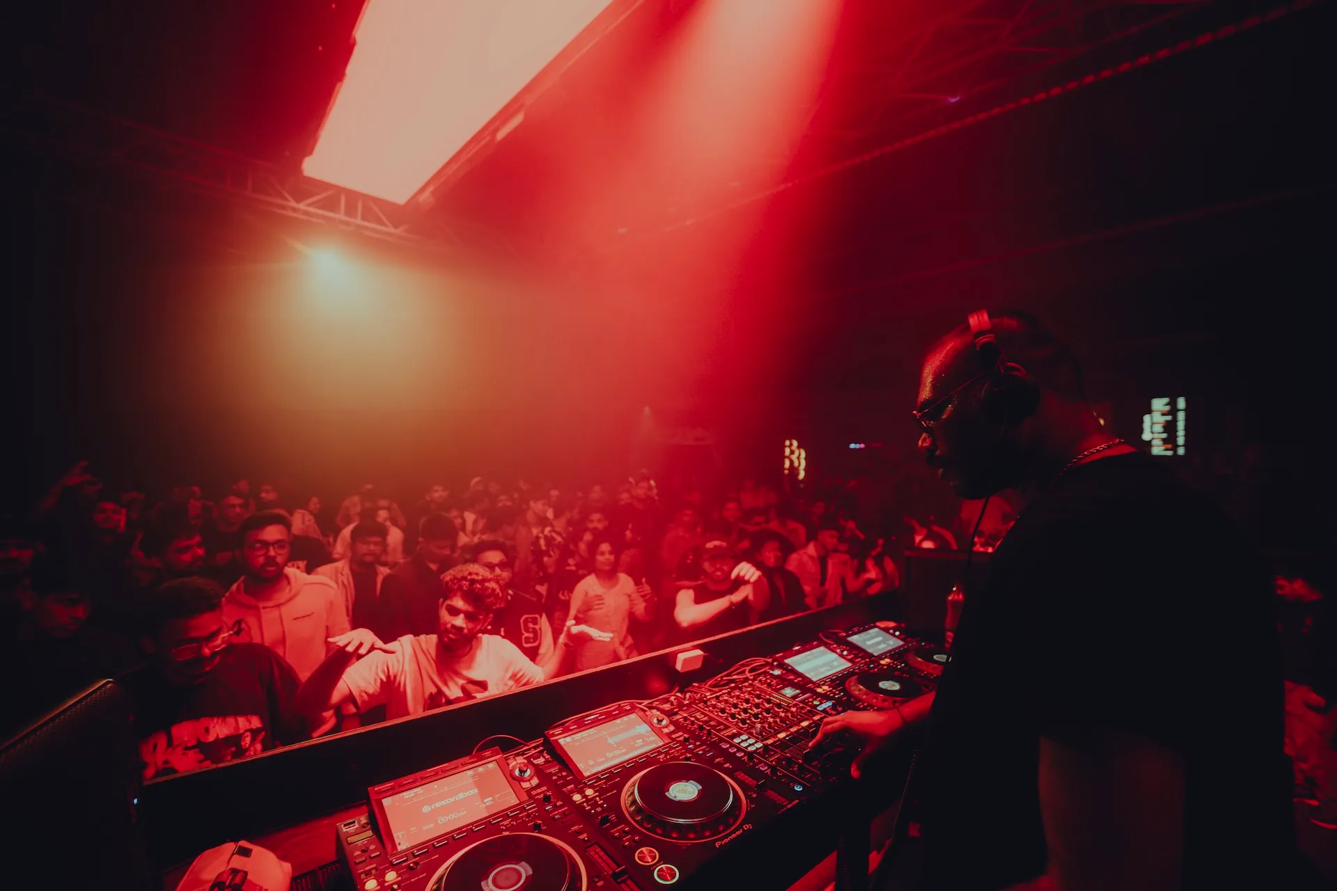 Raka Ashok behind the decks, crowd in red light